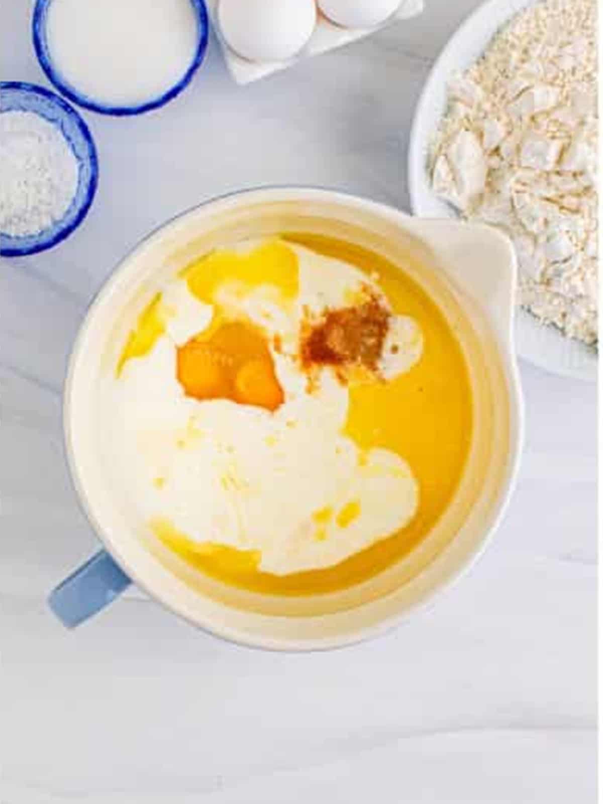Whisking eggs, milk, butter, and vanilla in a bowl for sheet pan pancakes.