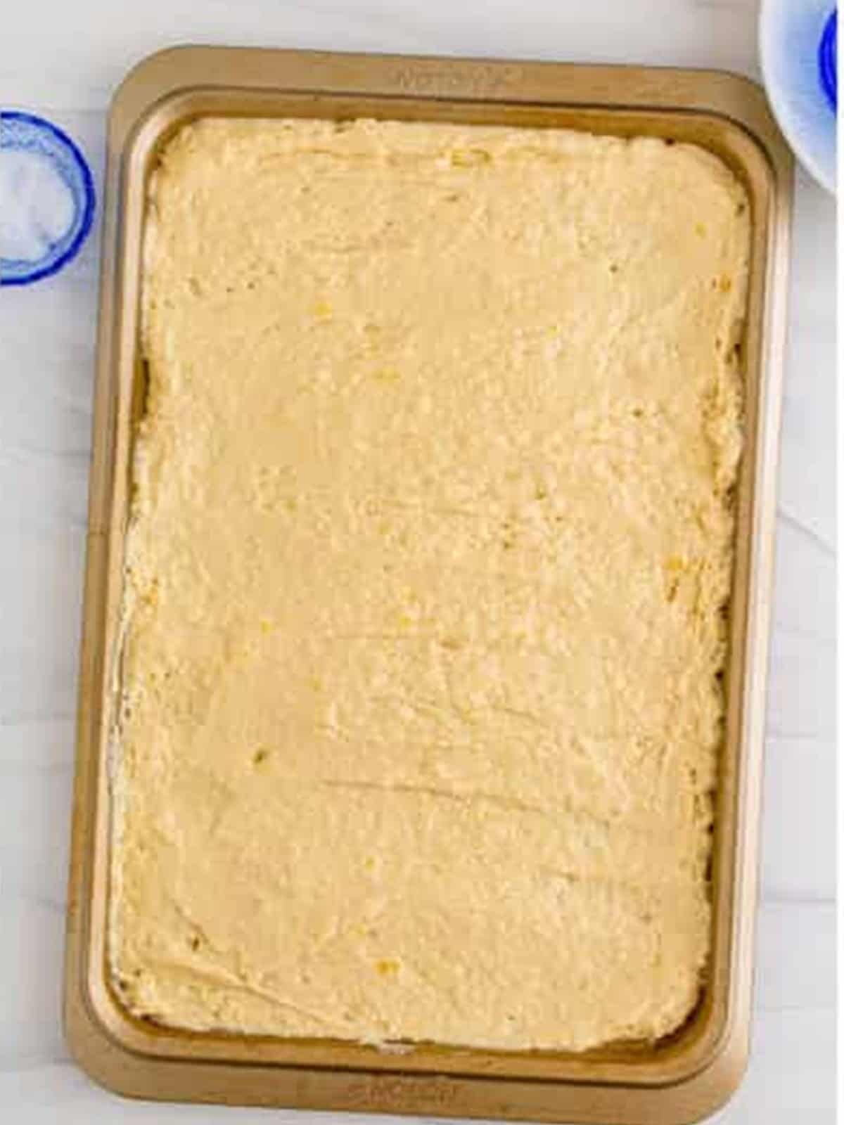 Pancake batter spread evenly in a sheet pan ready to bake.