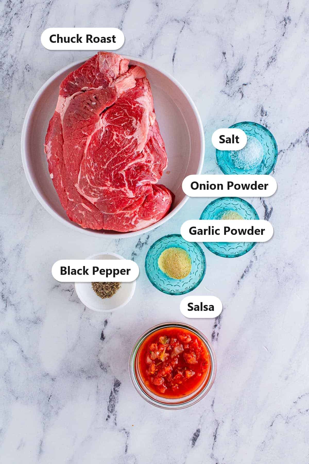 Labeled ingredients for slow cooker shredded beef tacos including chuck roast, salt, garlic powder, onion powder, black pepper, and salsa.