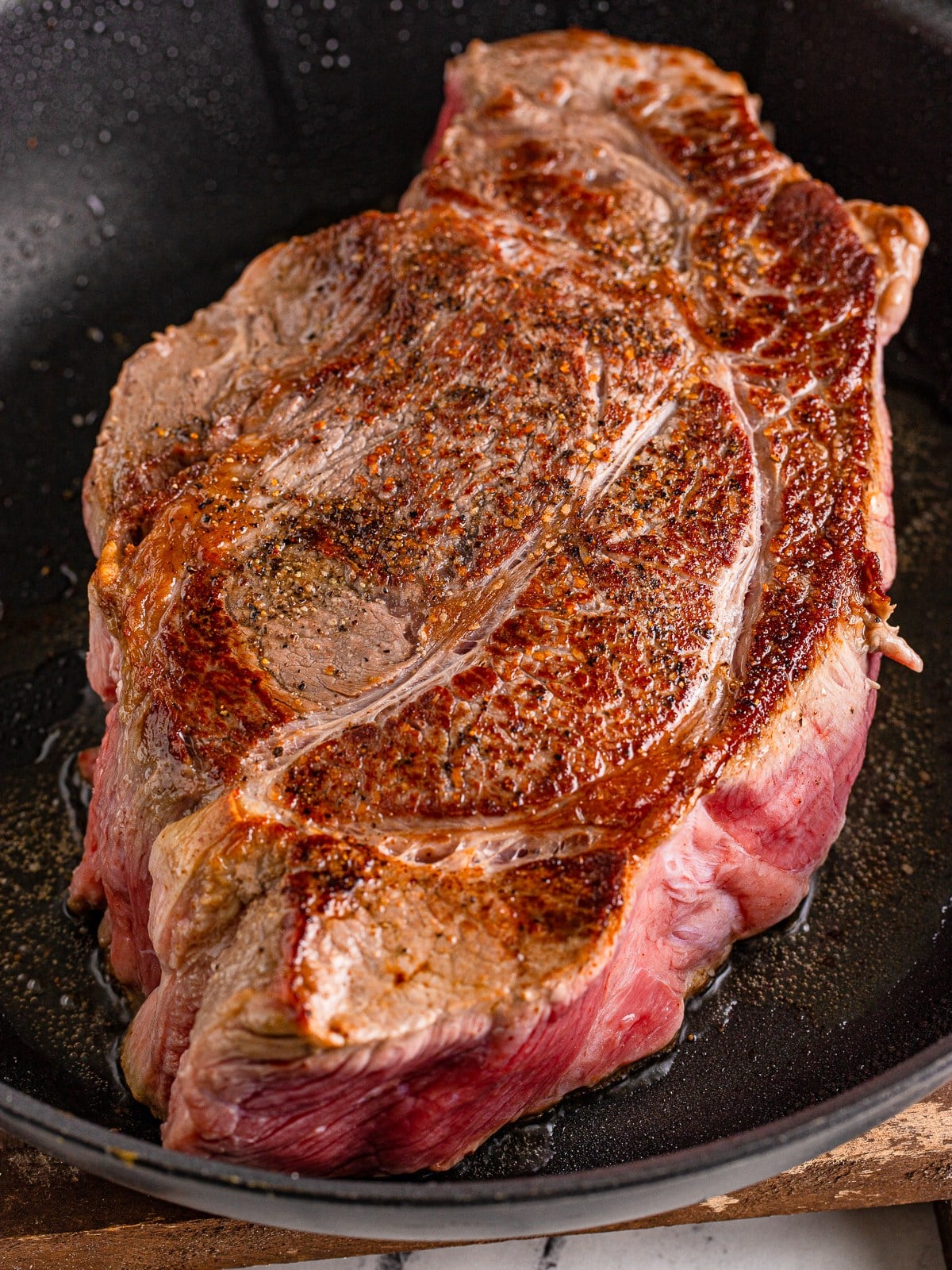 Seasoned chuck roast searing in a skillet for slow cooker shredded beef tacos.