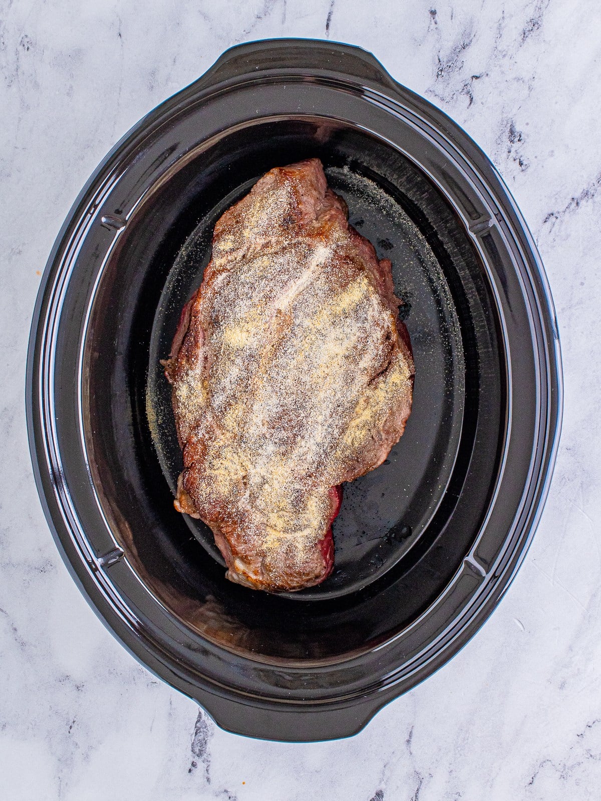 Seared chuck roast in a slow cooker for shredded beef tacos.