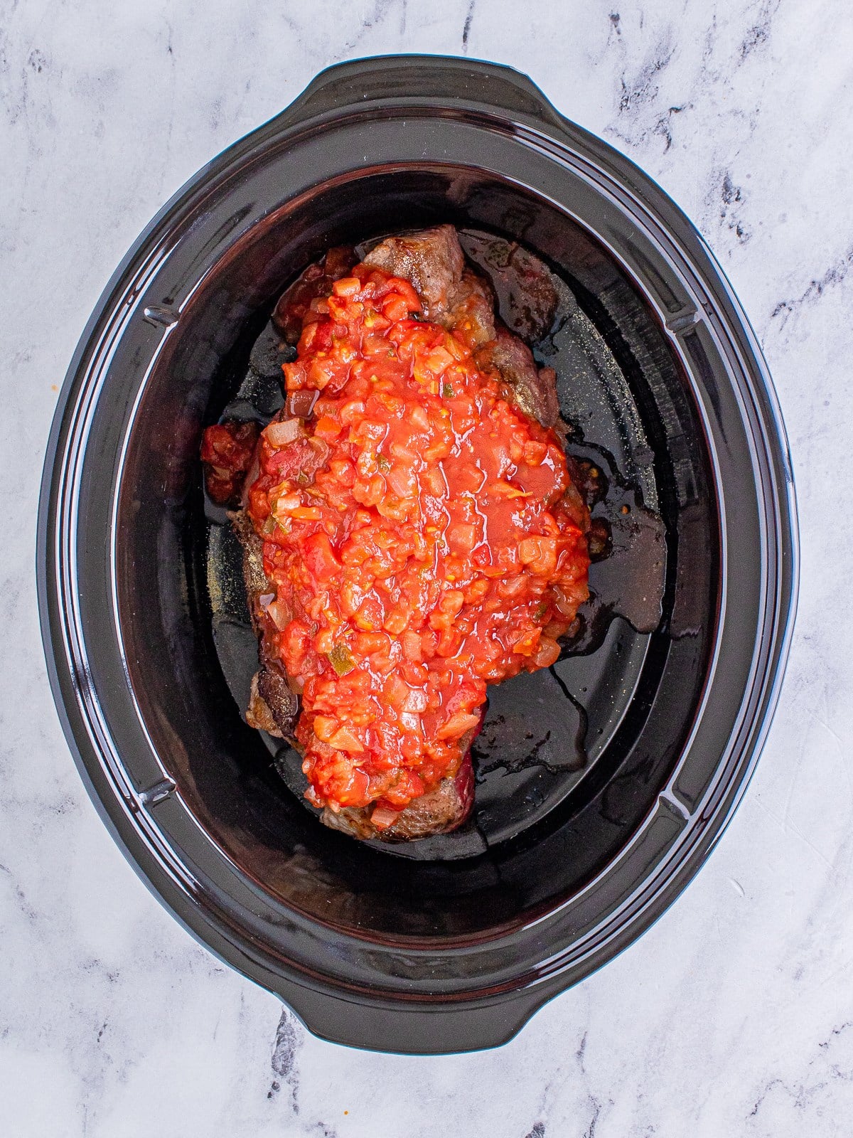 Salsa poured over the roast in the slow cooker for shredded beef tacos.