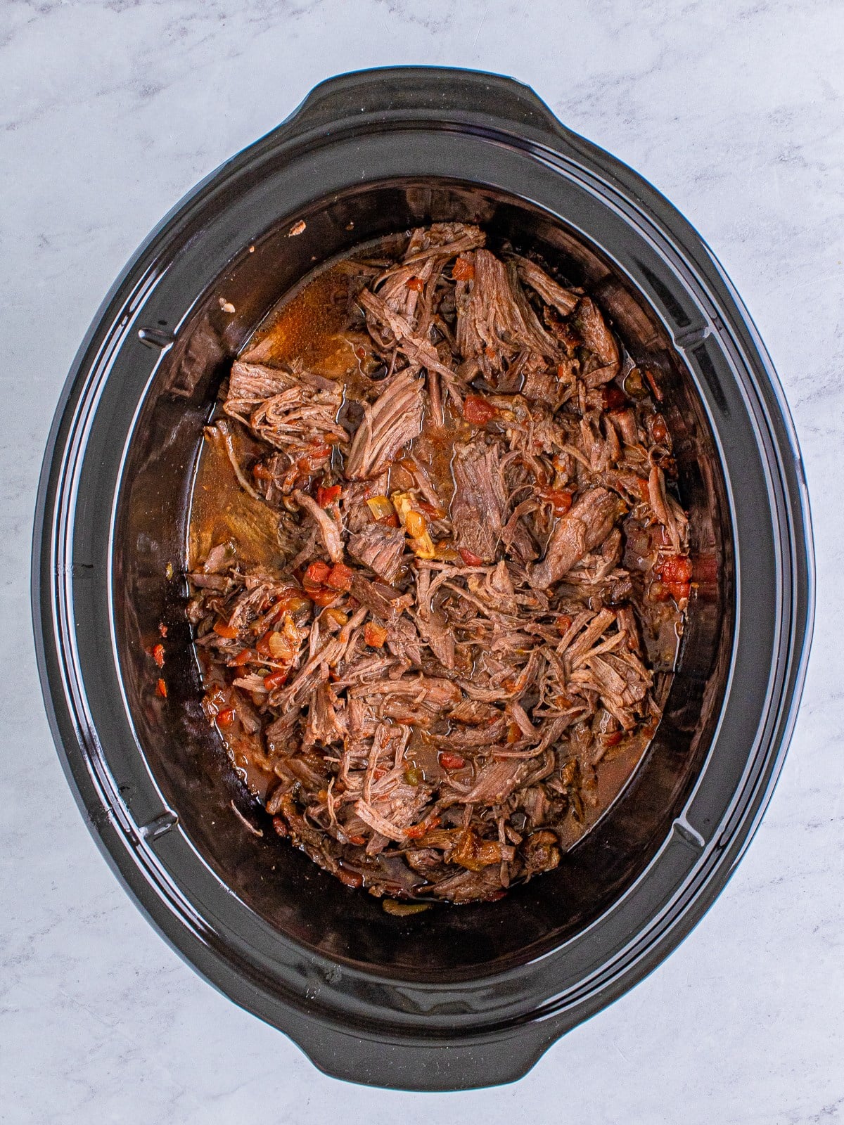 Shredded beef stirred into the juices in the slow cooker.
