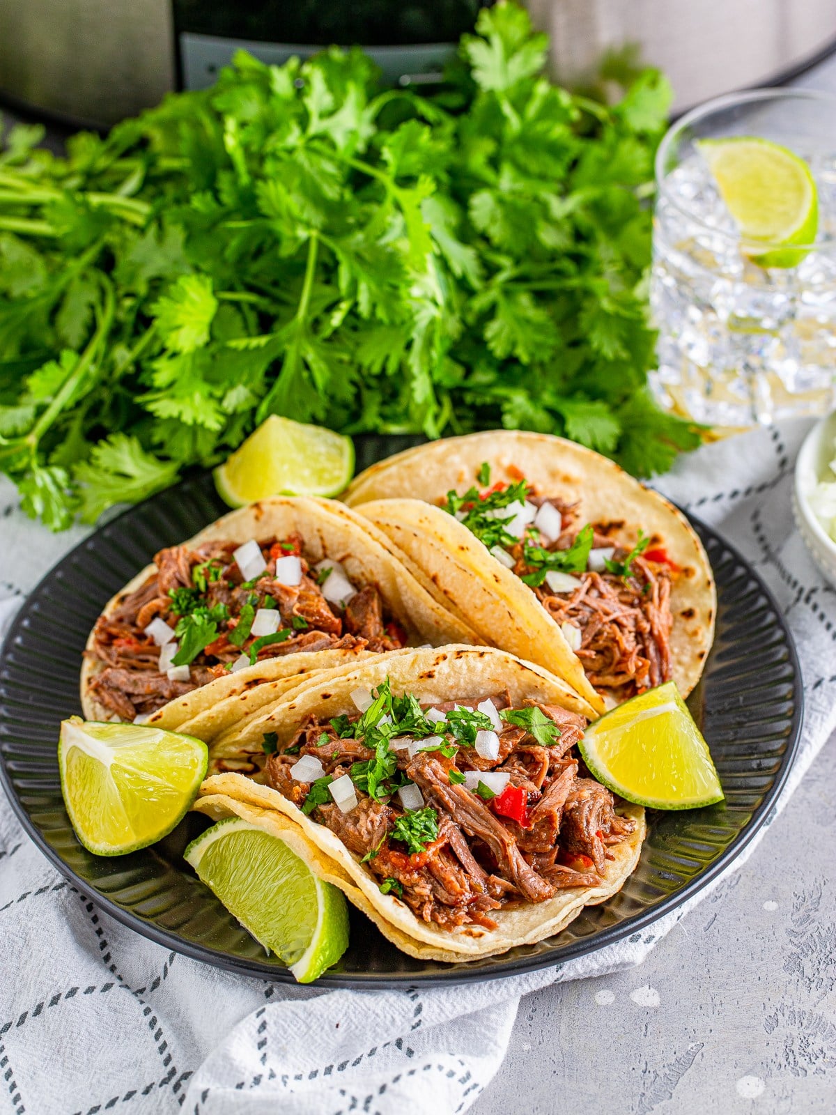 Slow cooker shredded beef tacos served in warm tortillas with toppings.