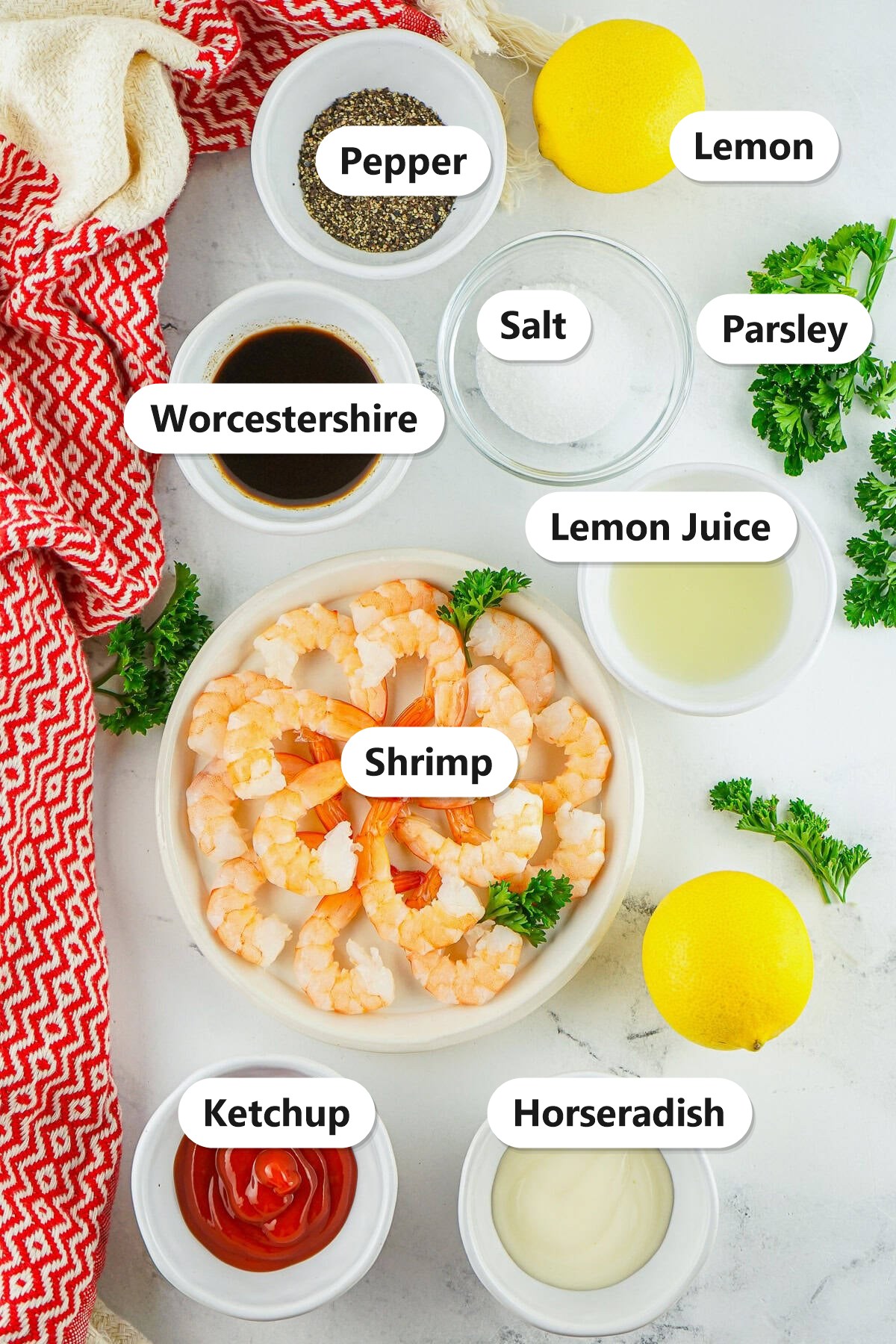 Labeled ingredients to make shrimp cocktail including shrimp, ketchup, horseradish, lemon juice, worcestershire, salt, pepper, parsley, and lemon.