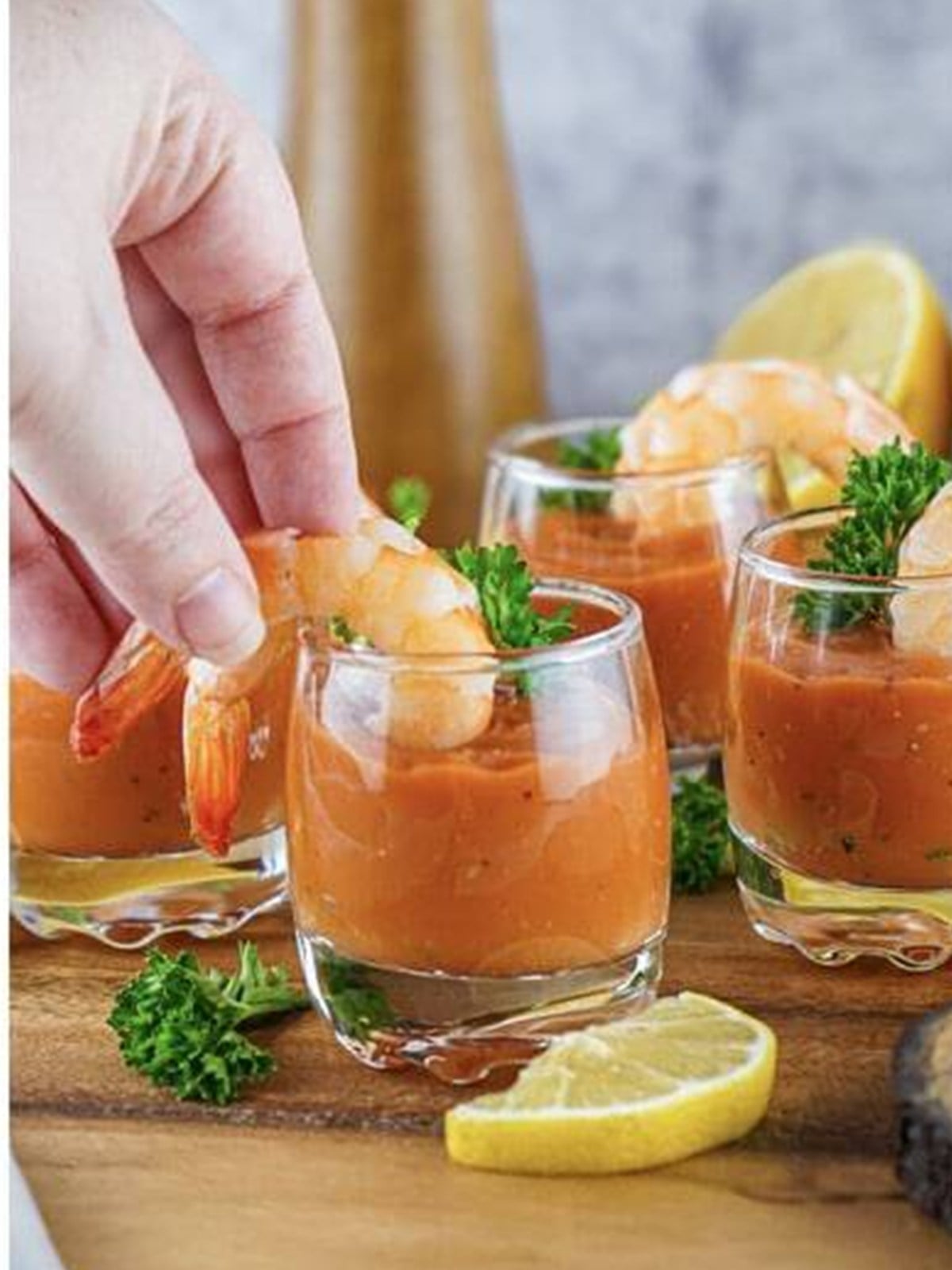 Chilled shrimp hung on the rims of shot glasses filled with cocktail sauce.