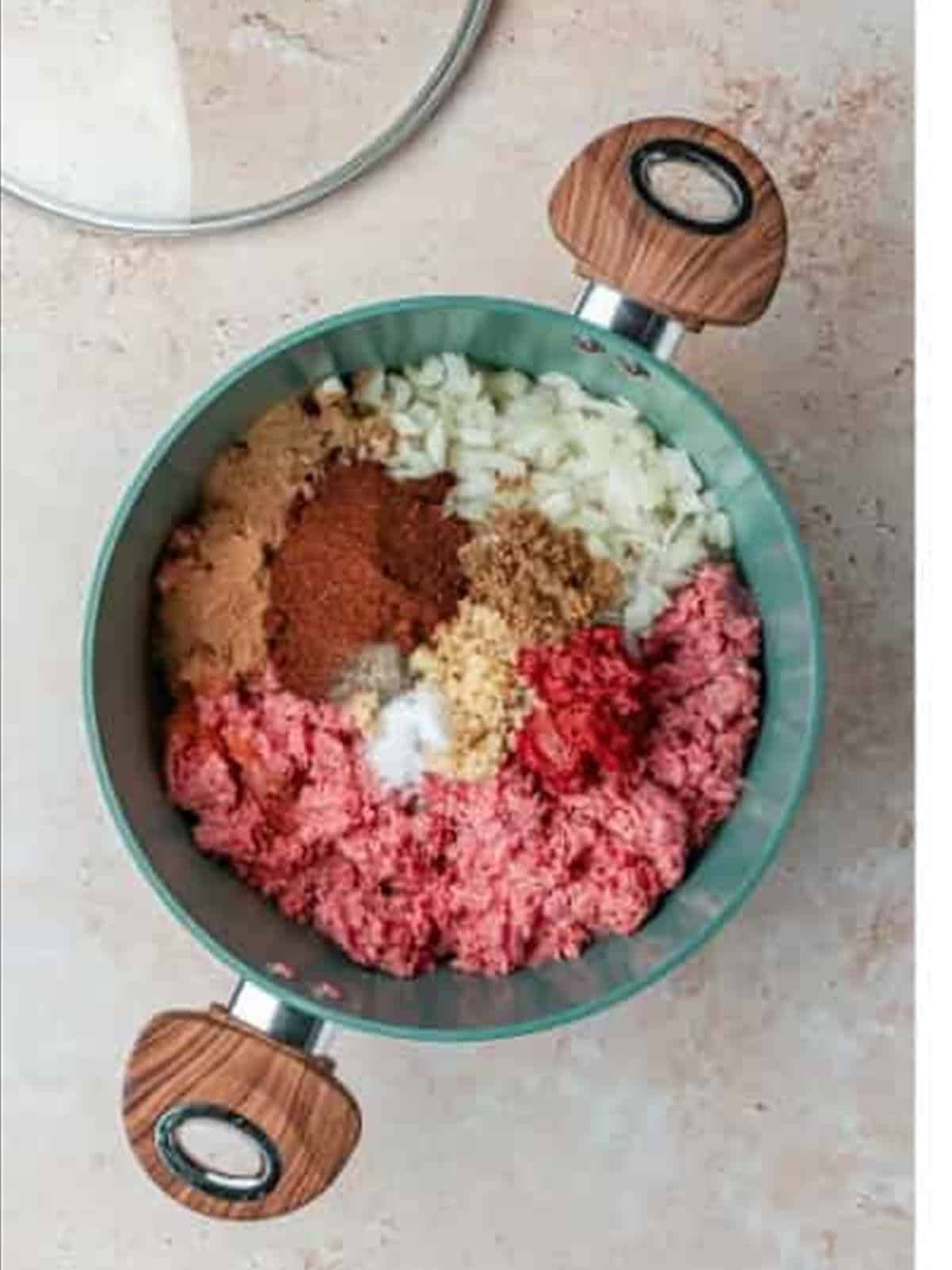 Ground beef, onion, garlic, tomato paste, and spices in a pot for Skyline chili recipe.