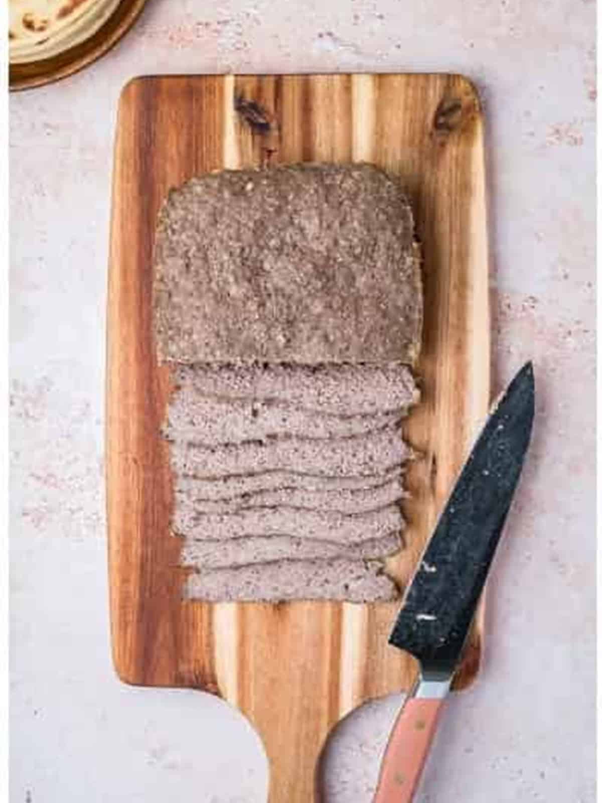 Chilled gyro loaf sliced thin on a wood cutting board