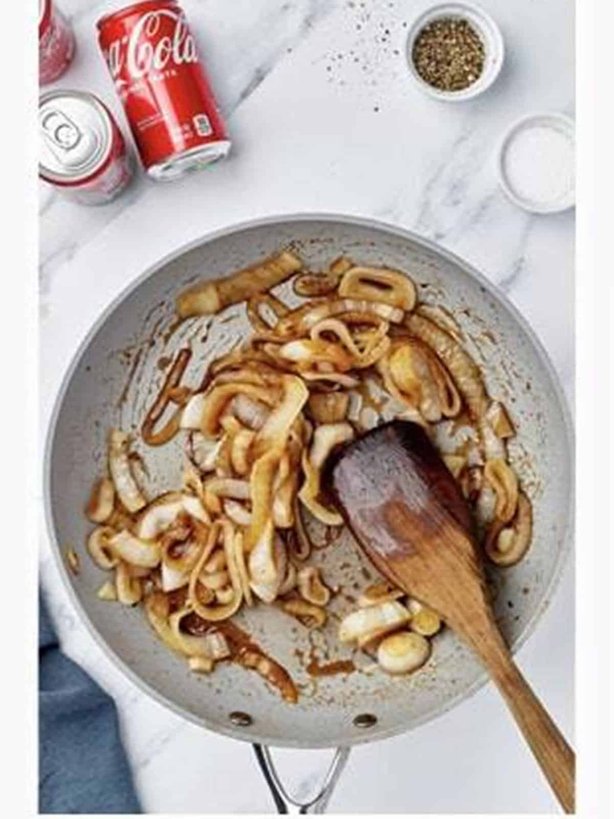 Onions caramelizing with Coca-Cola in a skillet for sloppy joe sliders.