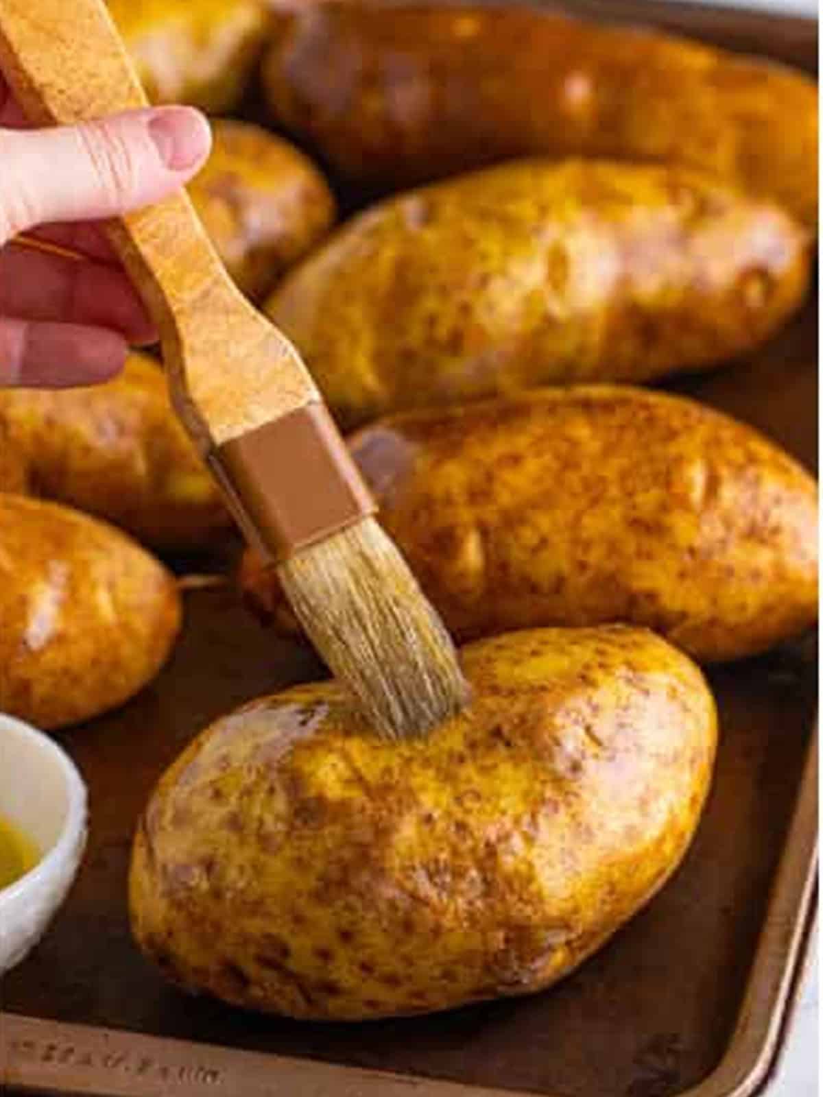 Brushing the potatoes with olive oil and seasoning with salt and pepper.