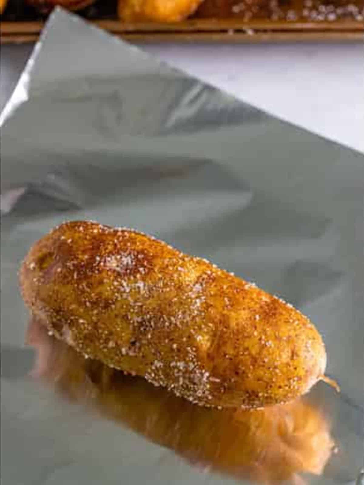 Seasoned russet potato wrapped individually in aluminum foil.