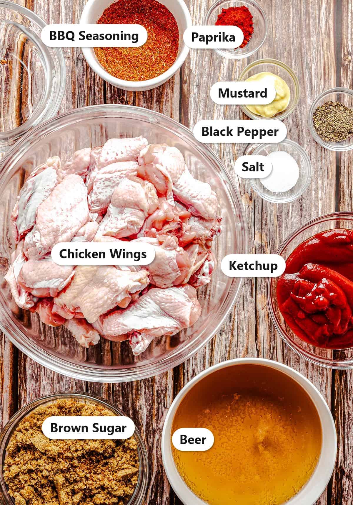 Labeled slow cooker BBQ chicken wings ingredients including chicken wings, ketchup, brown sugar, beer, mustard, and spices.