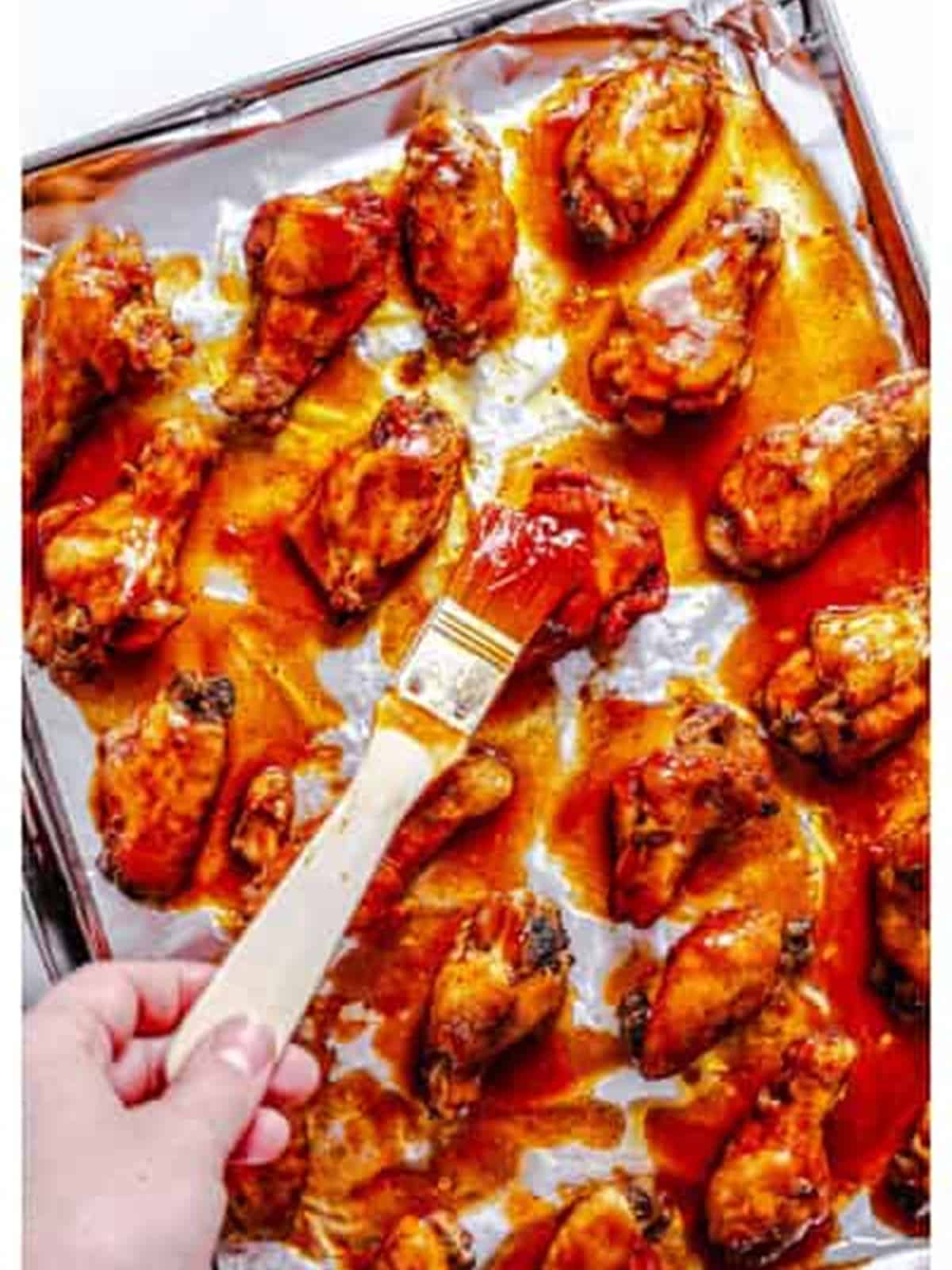 Basting the wings with BBQ sauce for slow cooker BBQ chicken wings.