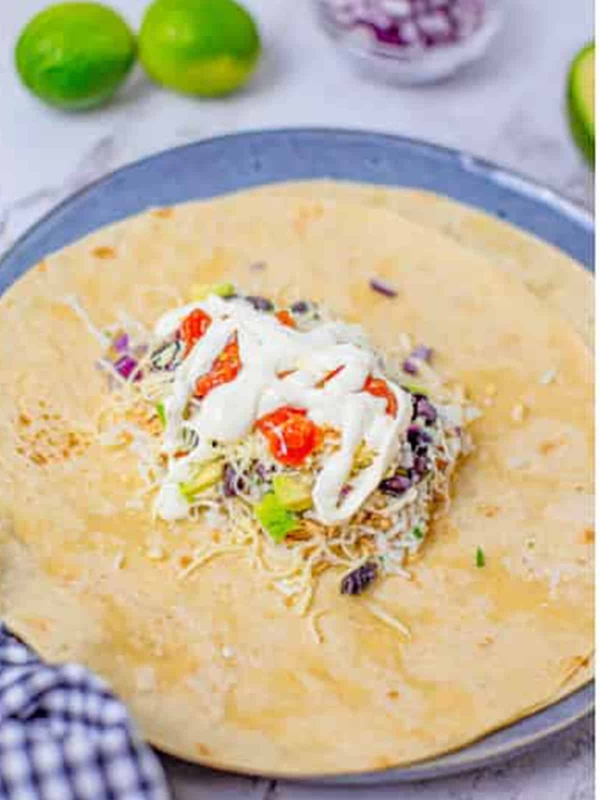 Burrito tortilla loaded with shredded chicken, cilantro lime rice, and toppings ready to roll.