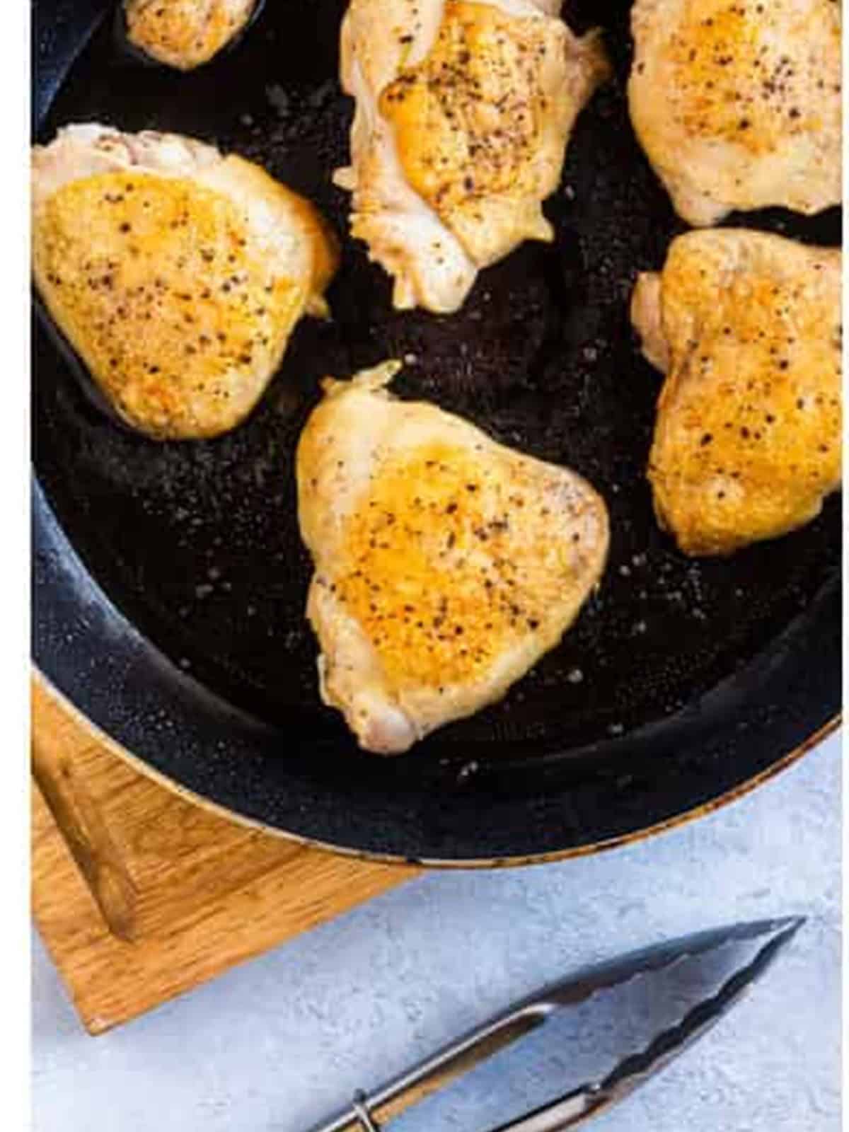 Seasoned chicken thighs seared golden brown in a skillet for slow cooker chicken marsala.
