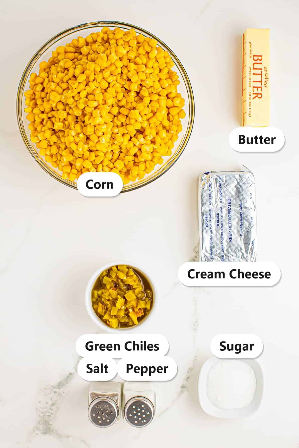 Labeled ingredients for slow cooker creamed corn including corn, butter, cream cheese, green chiles, sugar, salt, and pepper.