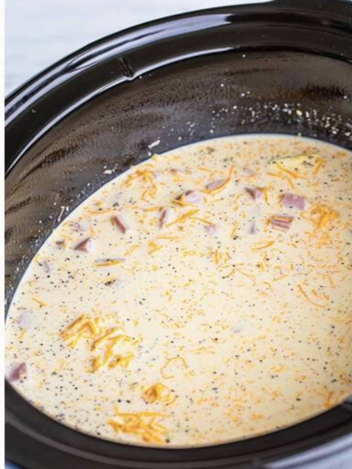 Milk and cheese stirred into the slow cooker mac and cheese before cooking.