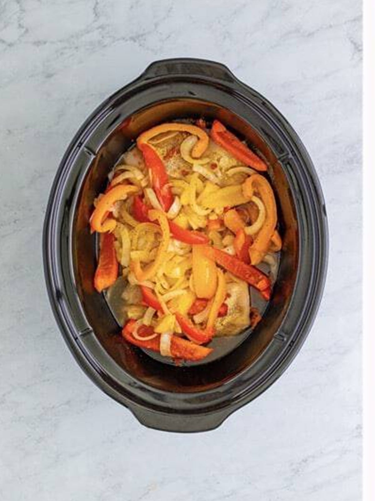 Sauteed peppers and onions layered over chicken in the slow cooker.