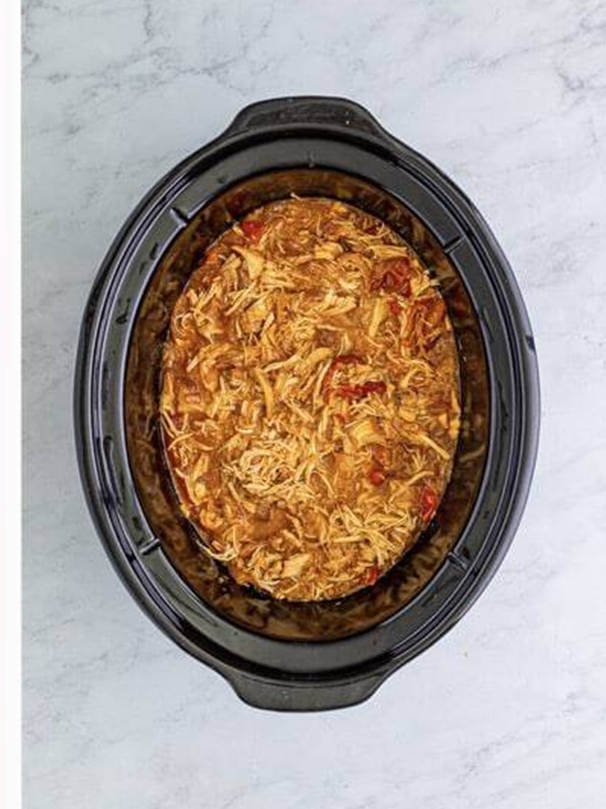 Shredded chicken mixed with peppers and onions in the slow cooker.