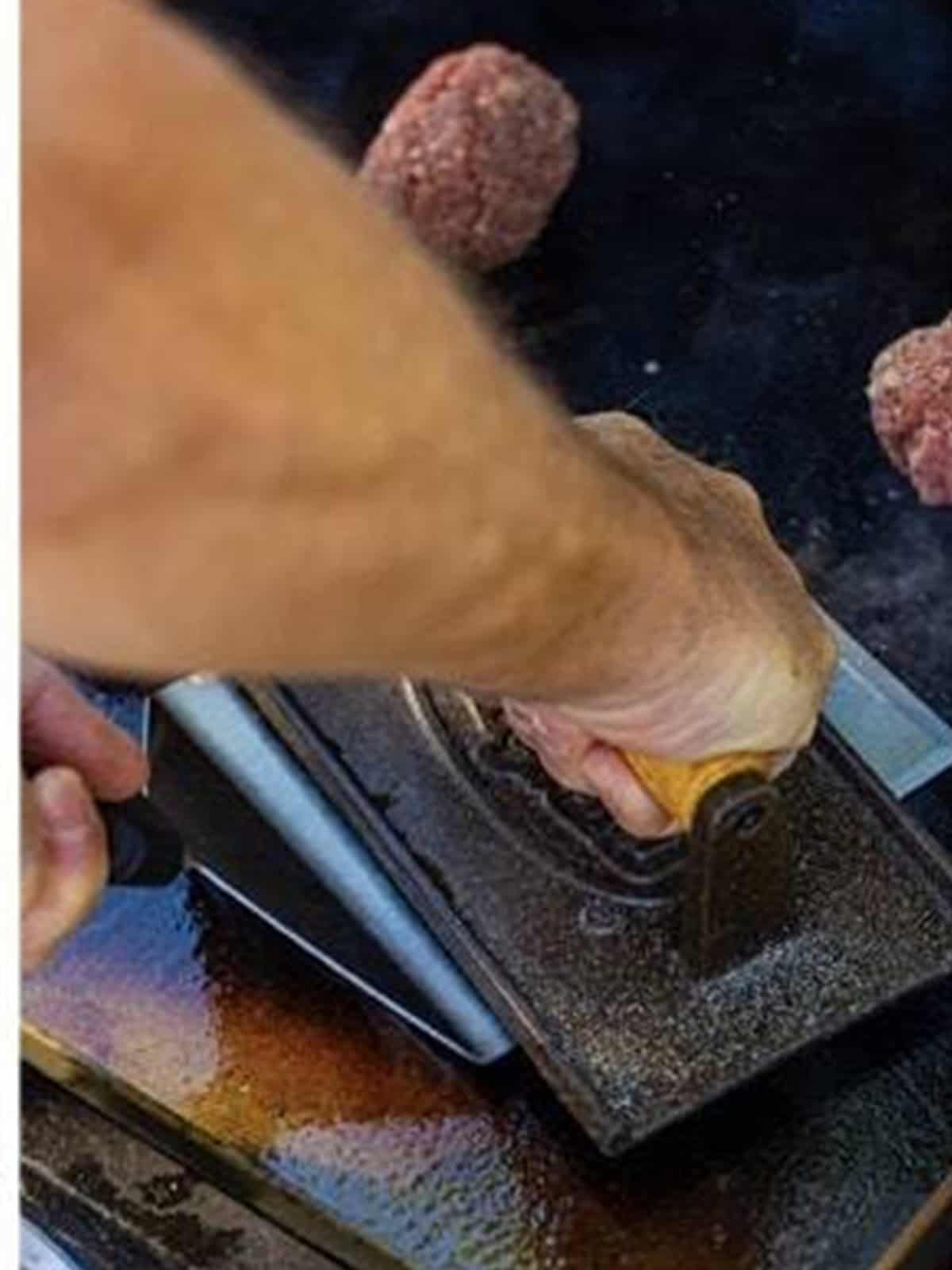 A ball of ground beef smashed thin on a hot griddle with a scraper for smash burgers.