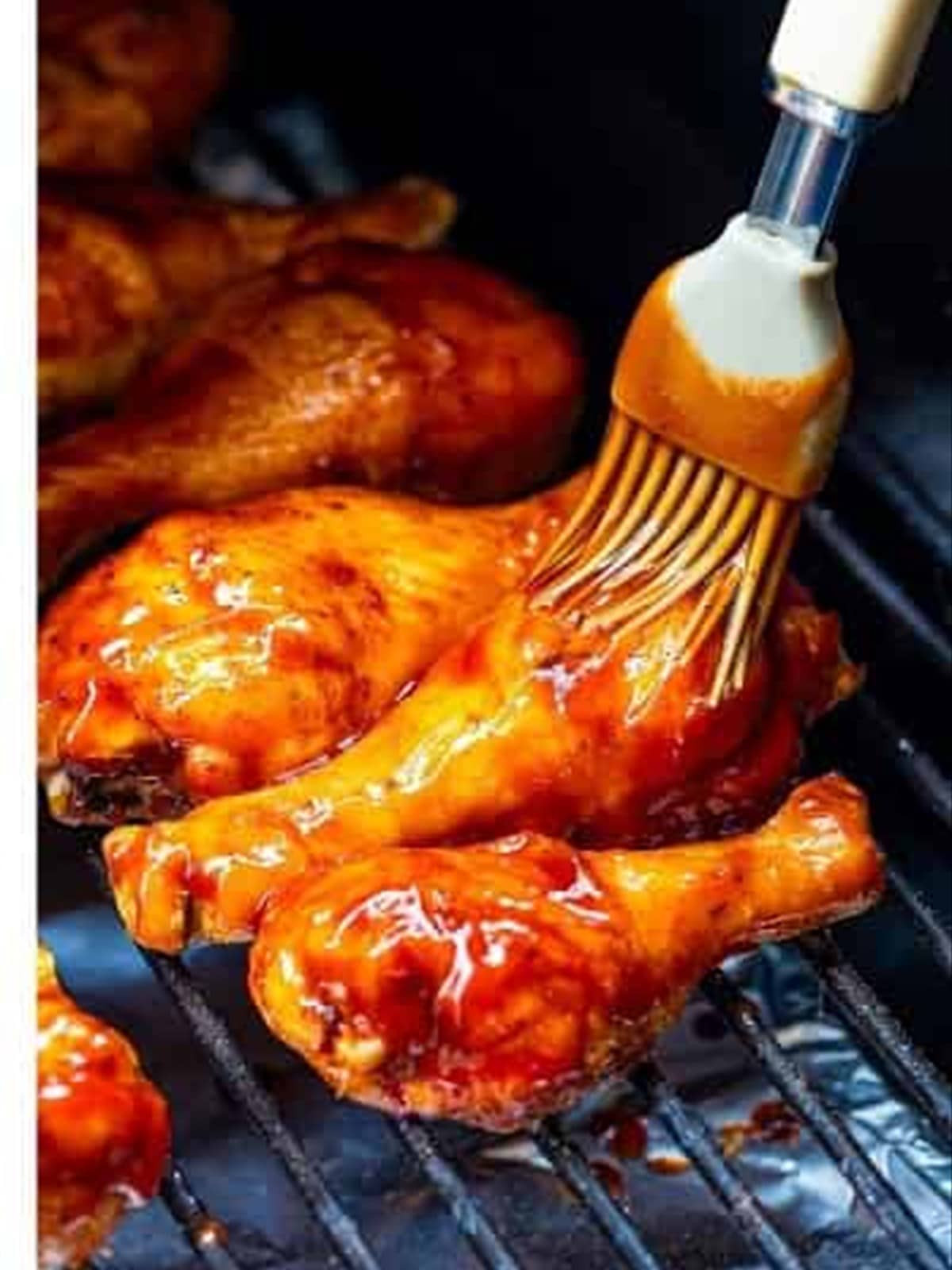 Basting smoked chicken legs with BBQ sauce on the smoker.