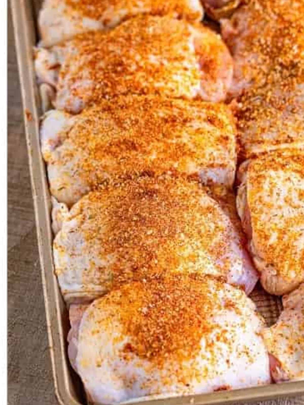 Chicken thighs coated with the dry rub on a sheet tray.
