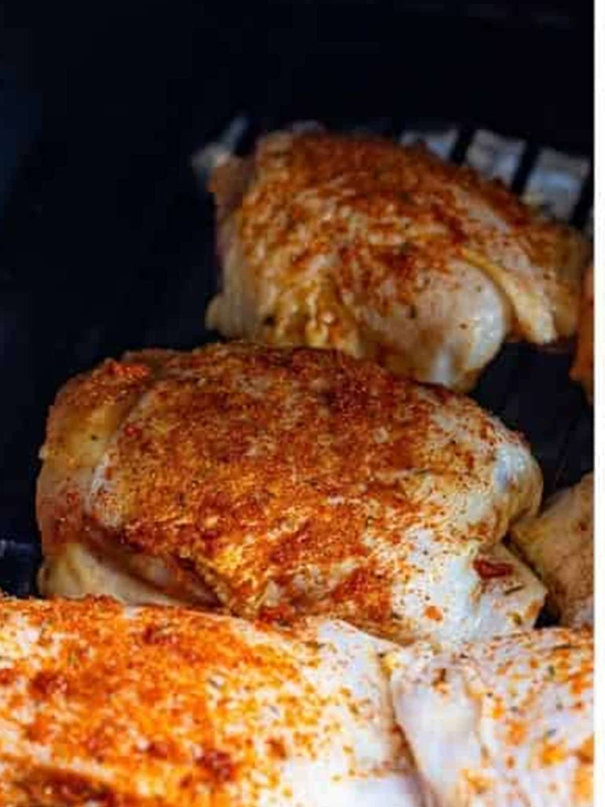Seasoned chicken thighs placed on the smoker grate.