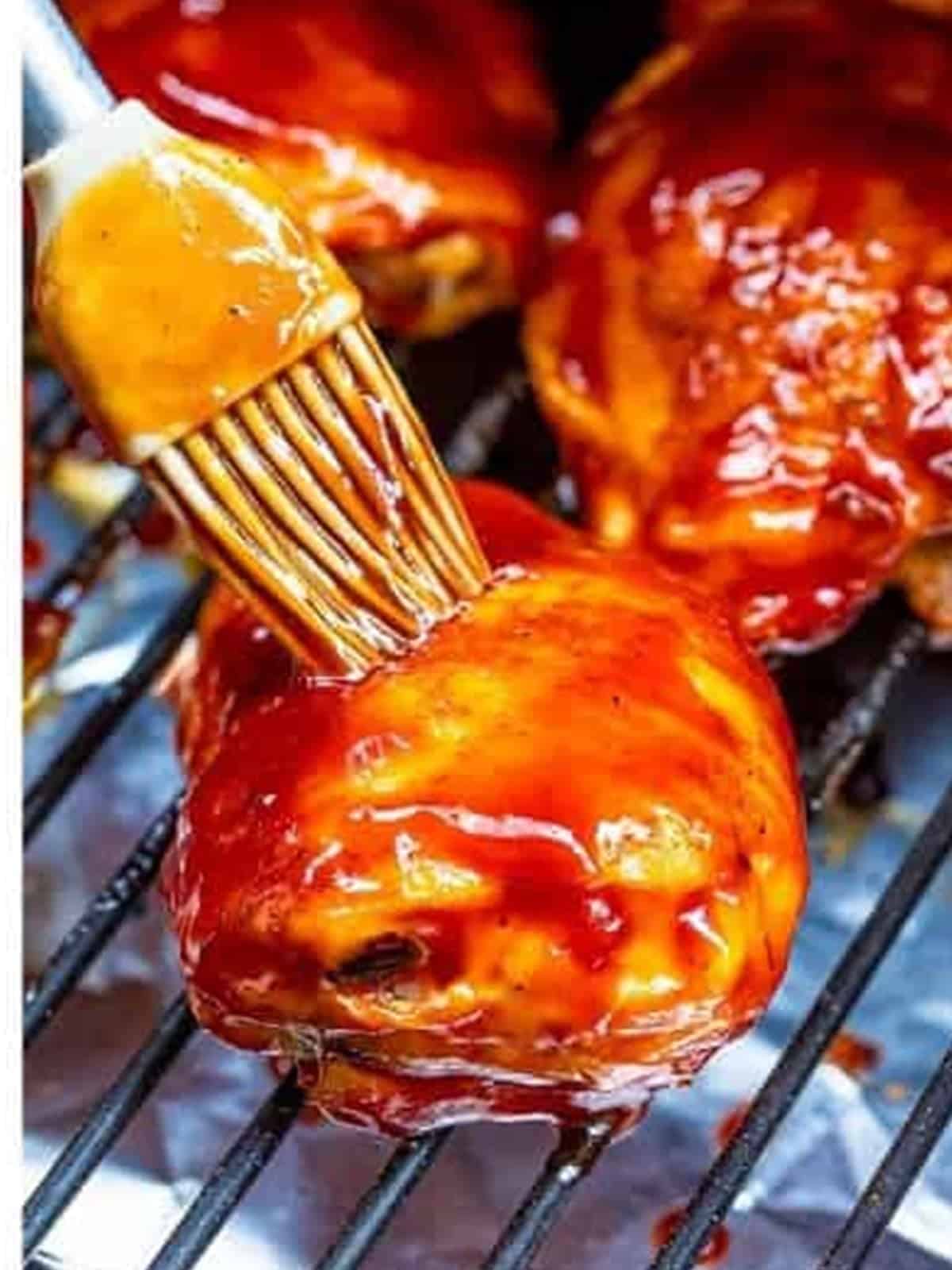 Smoked Chicken Thighs being brushed with BBQ sauce.