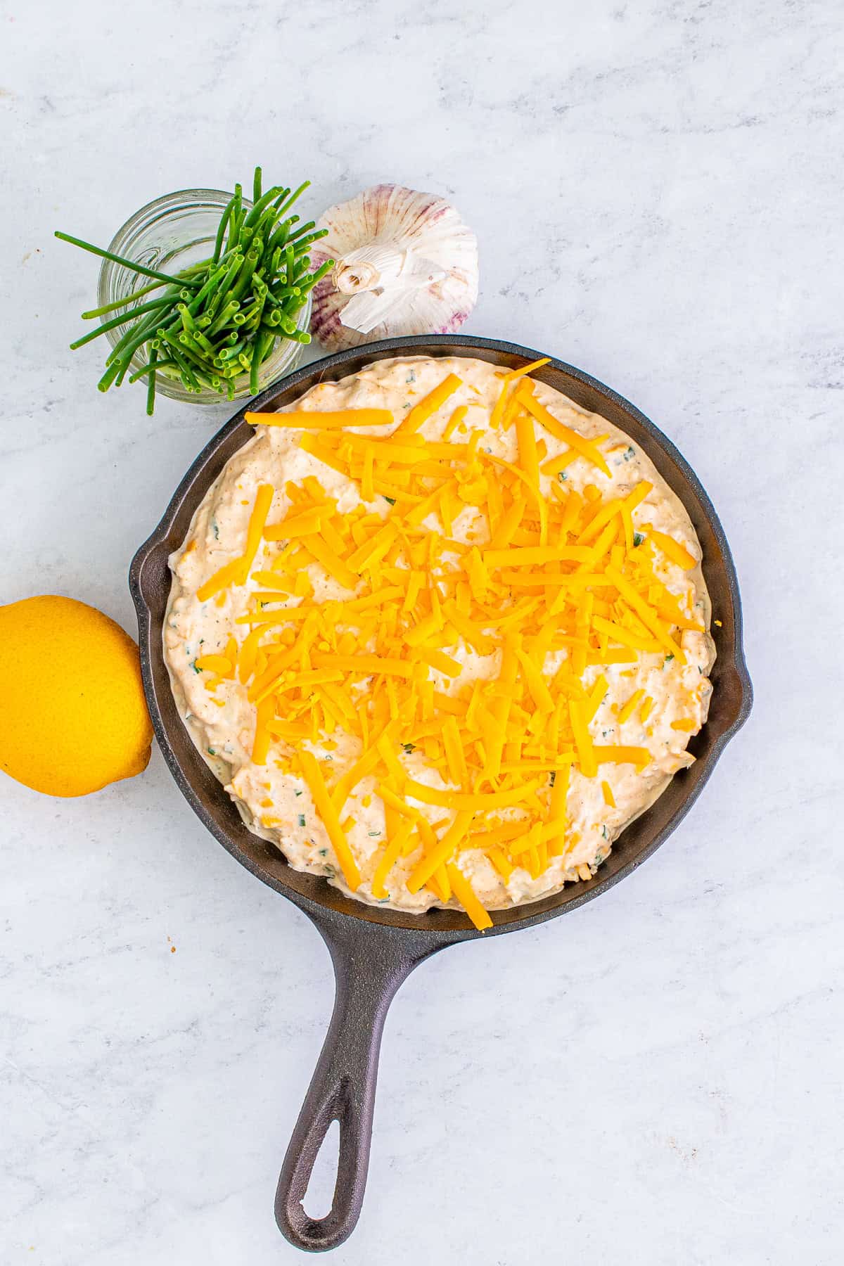 Smoked crab dip spread in a cast iron skillet and topped with shredded cheddar.