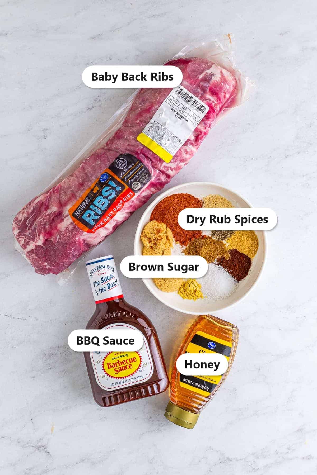 Labeled ingredients for smoked ribs including baby back ribs, dry rub spices, brown sugar, BBQ sauce, and honey on a marble surface.