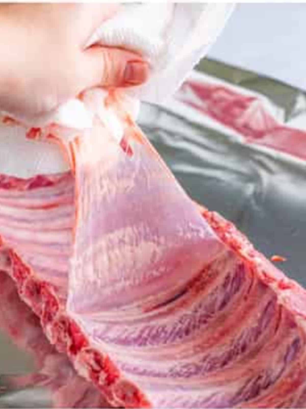 Removing the membrane from the back of a rack of baby back ribs.