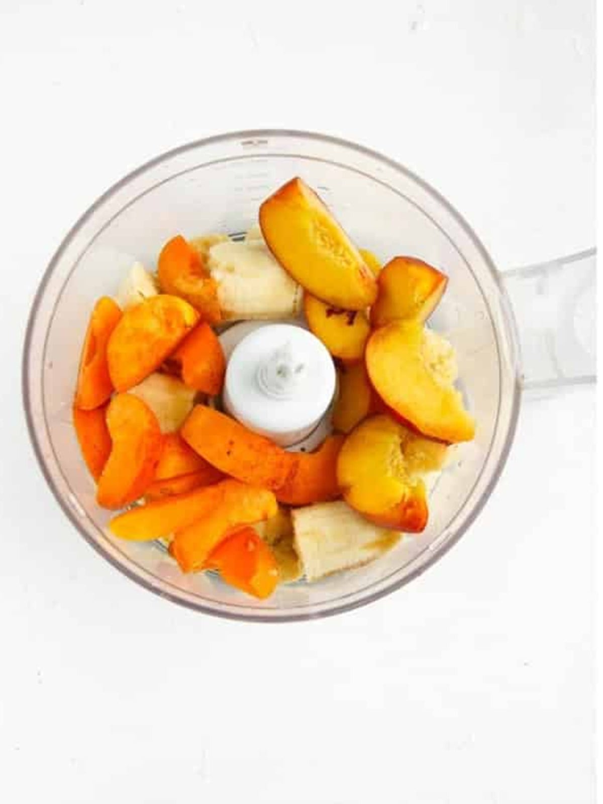 Apricots, peach, and banana added to a food processor to make a smoothie bowl.