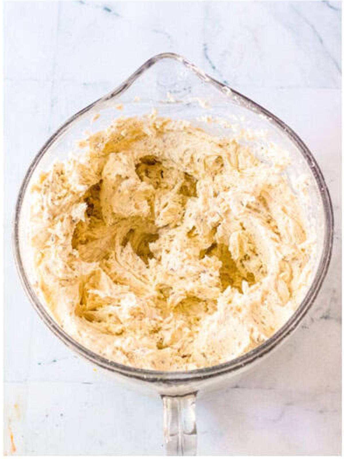 Fluffy whipped marshmallow buttercream frosting in a mixing bowl for s'mores cake.