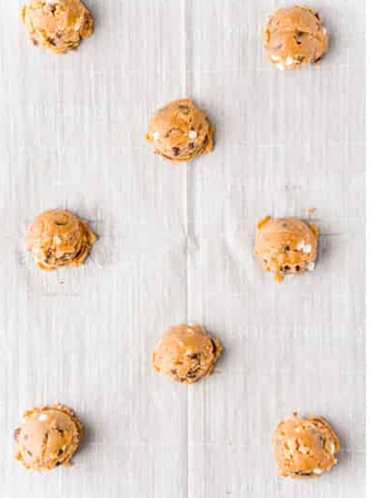 Scooped cookie dough balls on a parchment-lined baking sheet.