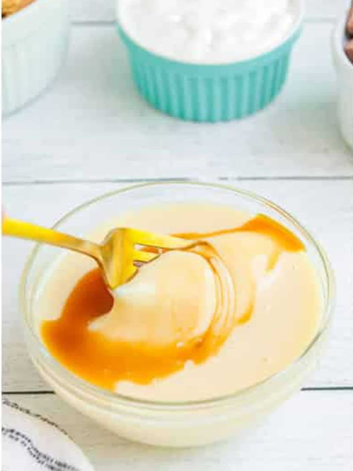 Sweetened condensed milk and vanilla whisked together in a glass bowl.