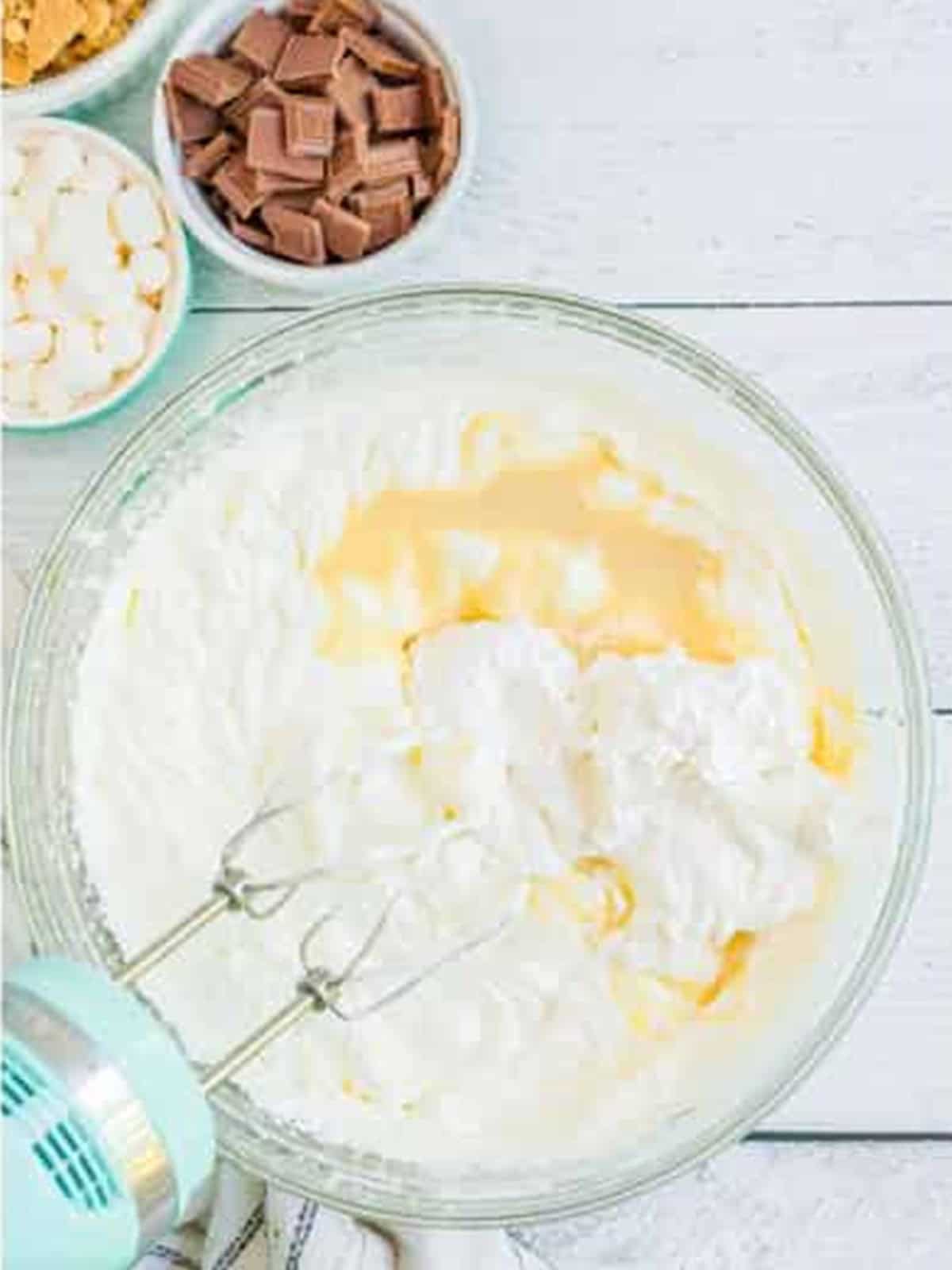 Whipped cream with condensed milk and marshmallow fluff being folded together.