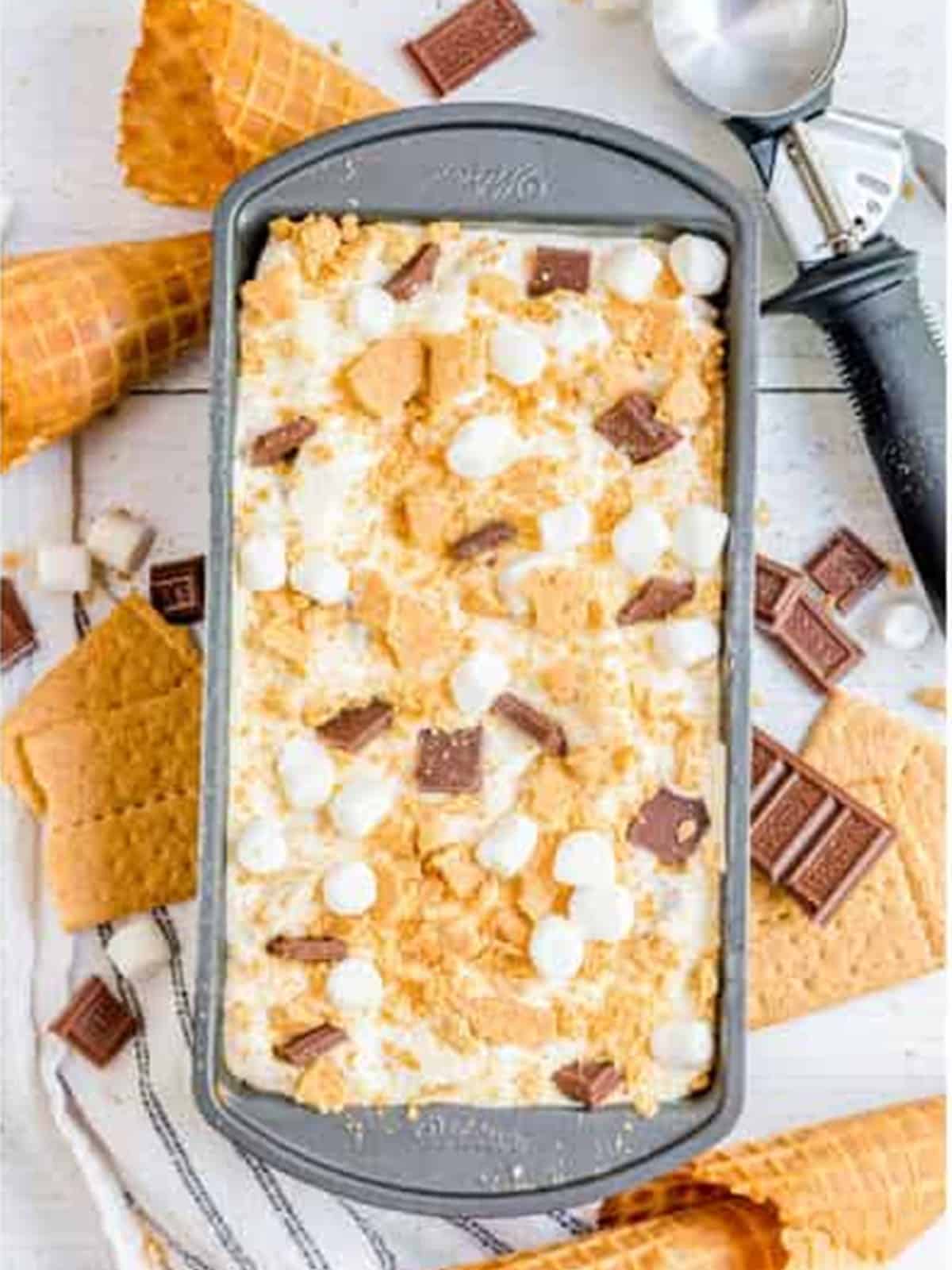 Smores ice cream topped with graham crackers, marshmallows, and chocolate before freezing.