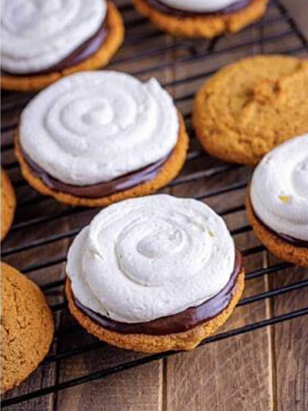 Piping marshmallow filling onto whoopie pie cookies to assemble.