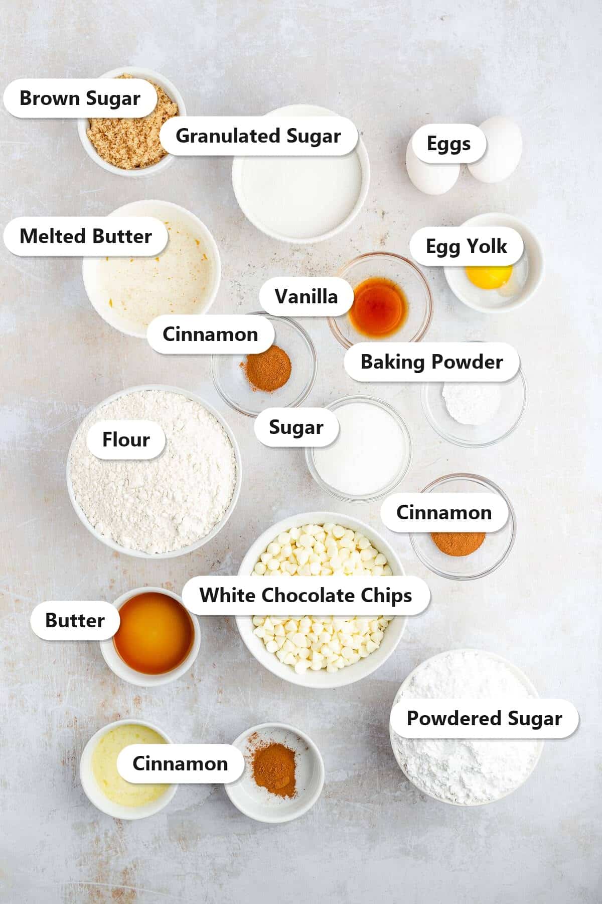 Labeled ingredients for snickerdoodle sandwich cookies including butter, granulated and brown sugar, eggs, flour, cinnamon, and white chocolate chips.