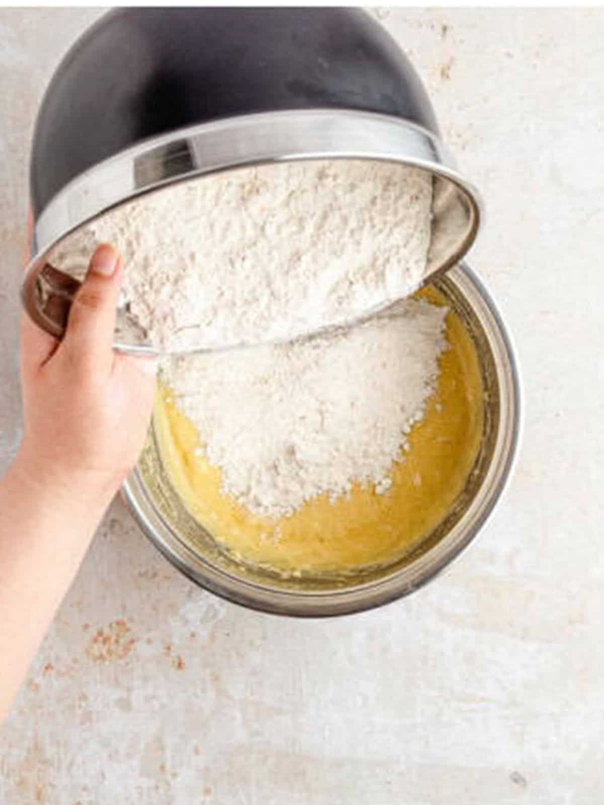Adding flour, baking powder, and cinnamon to the snickerdoodle cookie dough.