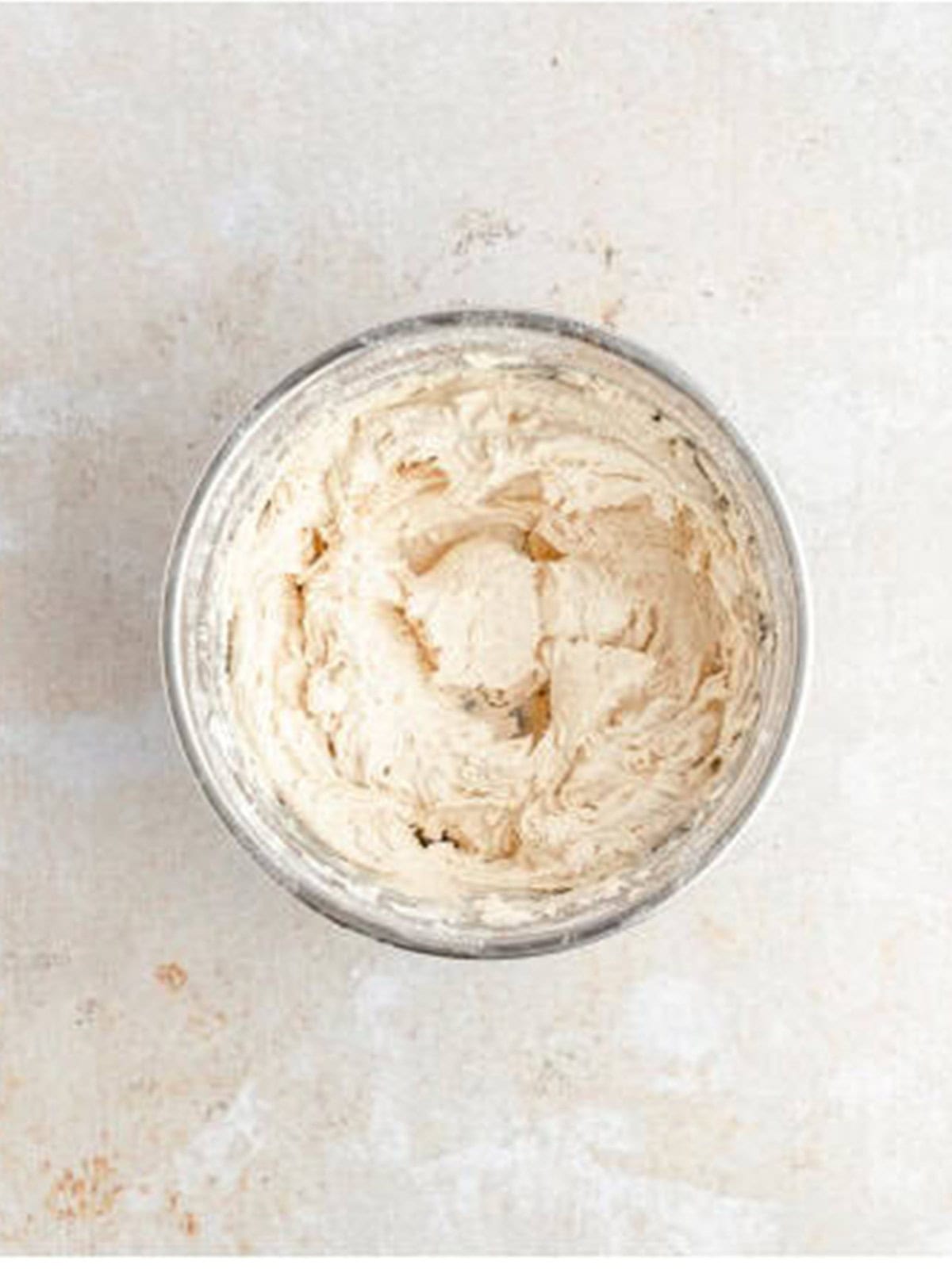 Whipped white chocolate cinnamon frosting in a glass bowl for the cookie filling.