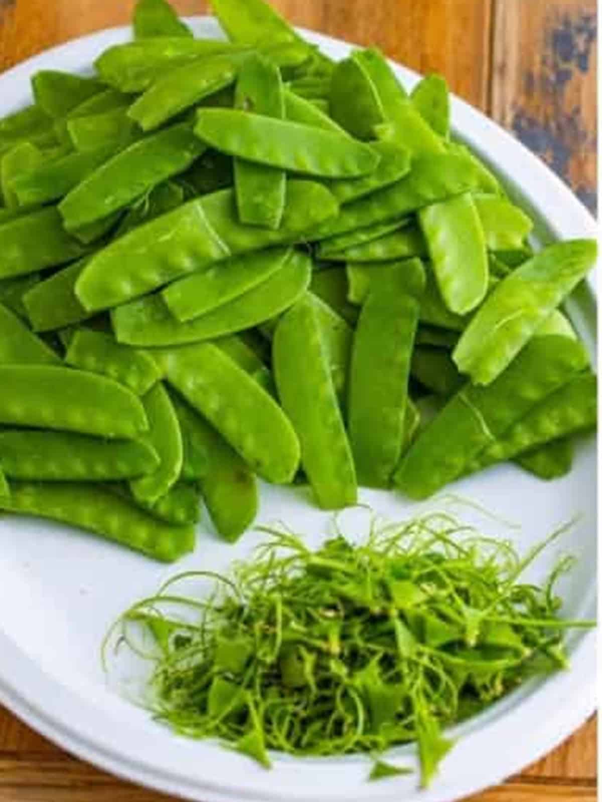 Cleaned snow peas on a plate with the strings removed for the snow peas recipe.
