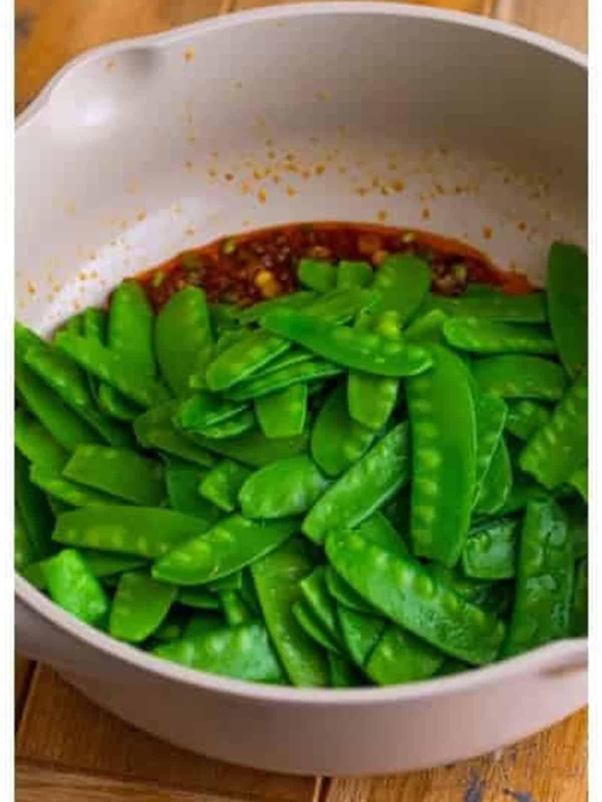 Blanched snow peas added to the garlic ginger sauce in the pan.
