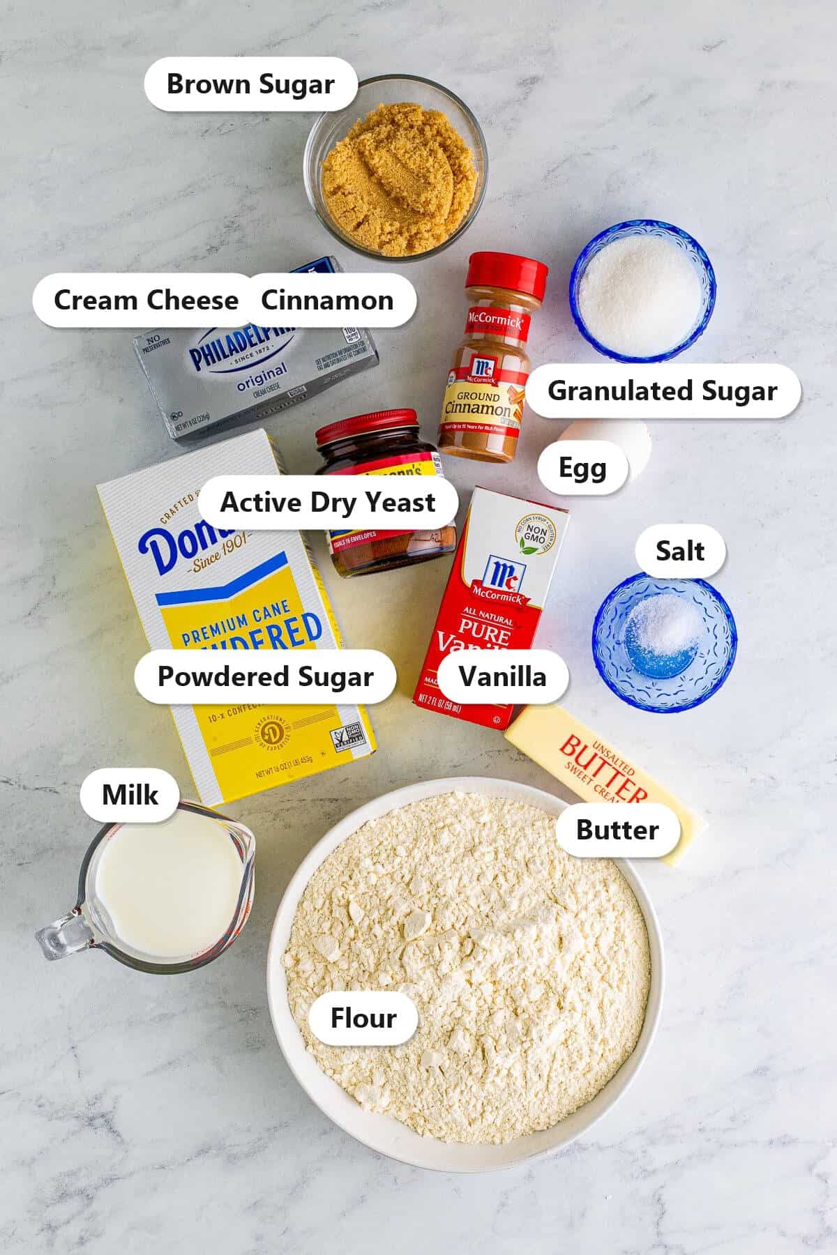 Labeled ingredients for soft cinnamon rolls including flour, milk, butter, yeast, sugars, cinnamon, cream cheese, and vanilla.