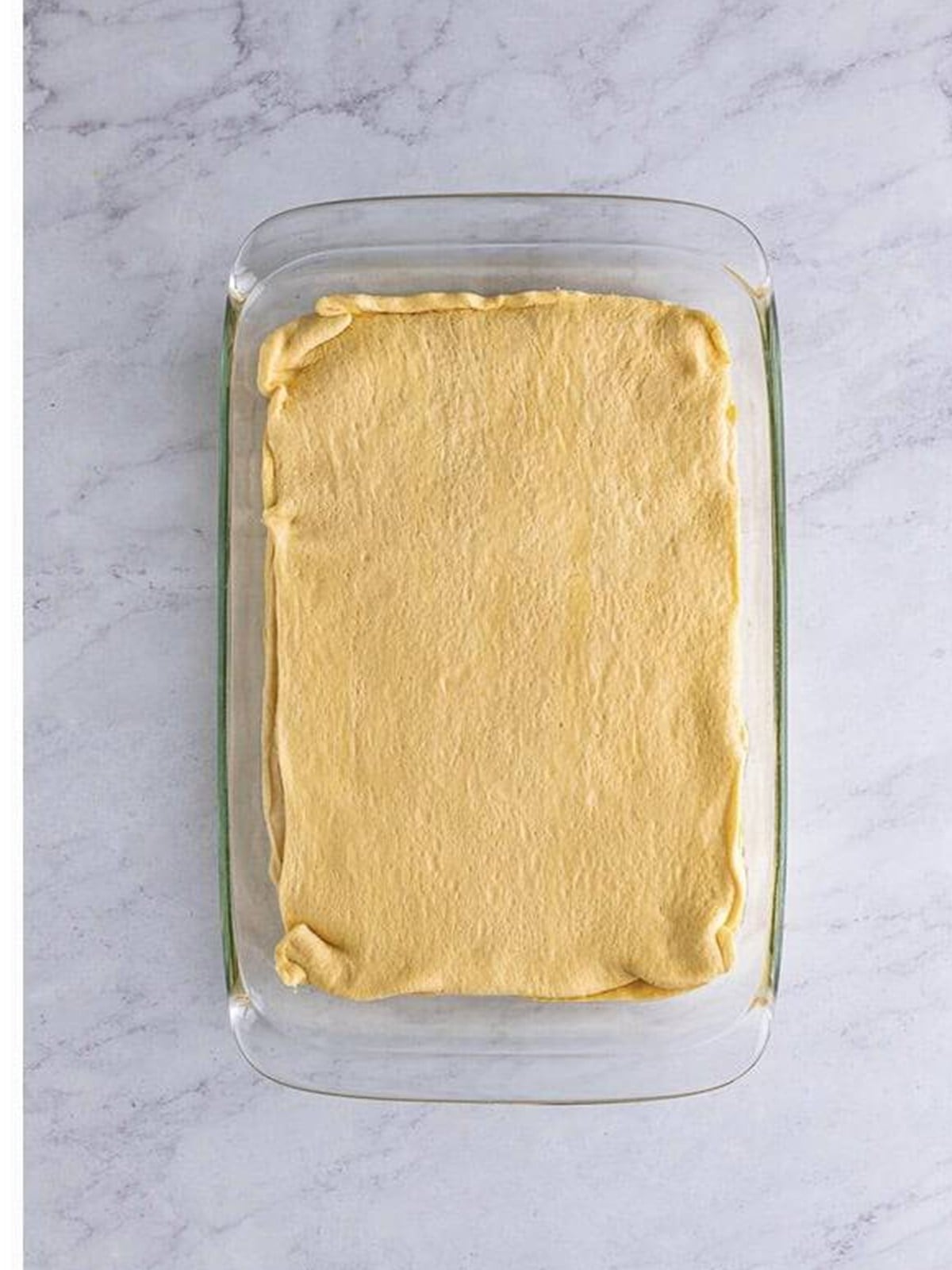 A second crescent dough sheet layered over the cheesecake filling.