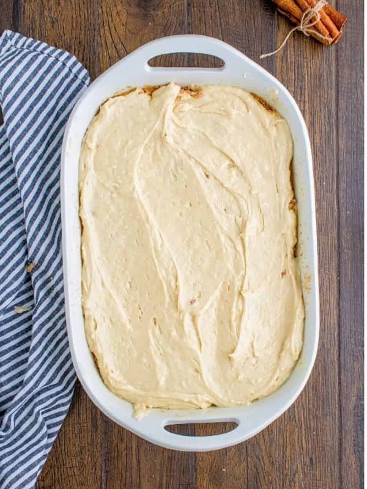 Sour cream coffee cake batter spread evenly in a baking dish.