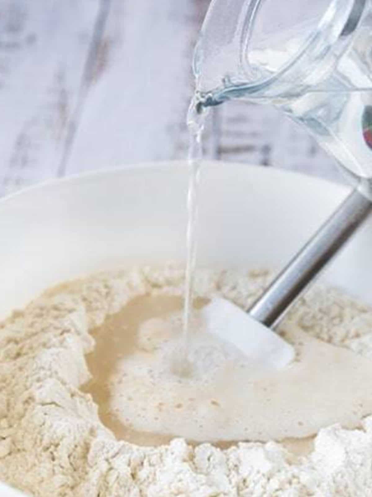 Warm water poured into the flour and starter for sourdough bread recipe.
