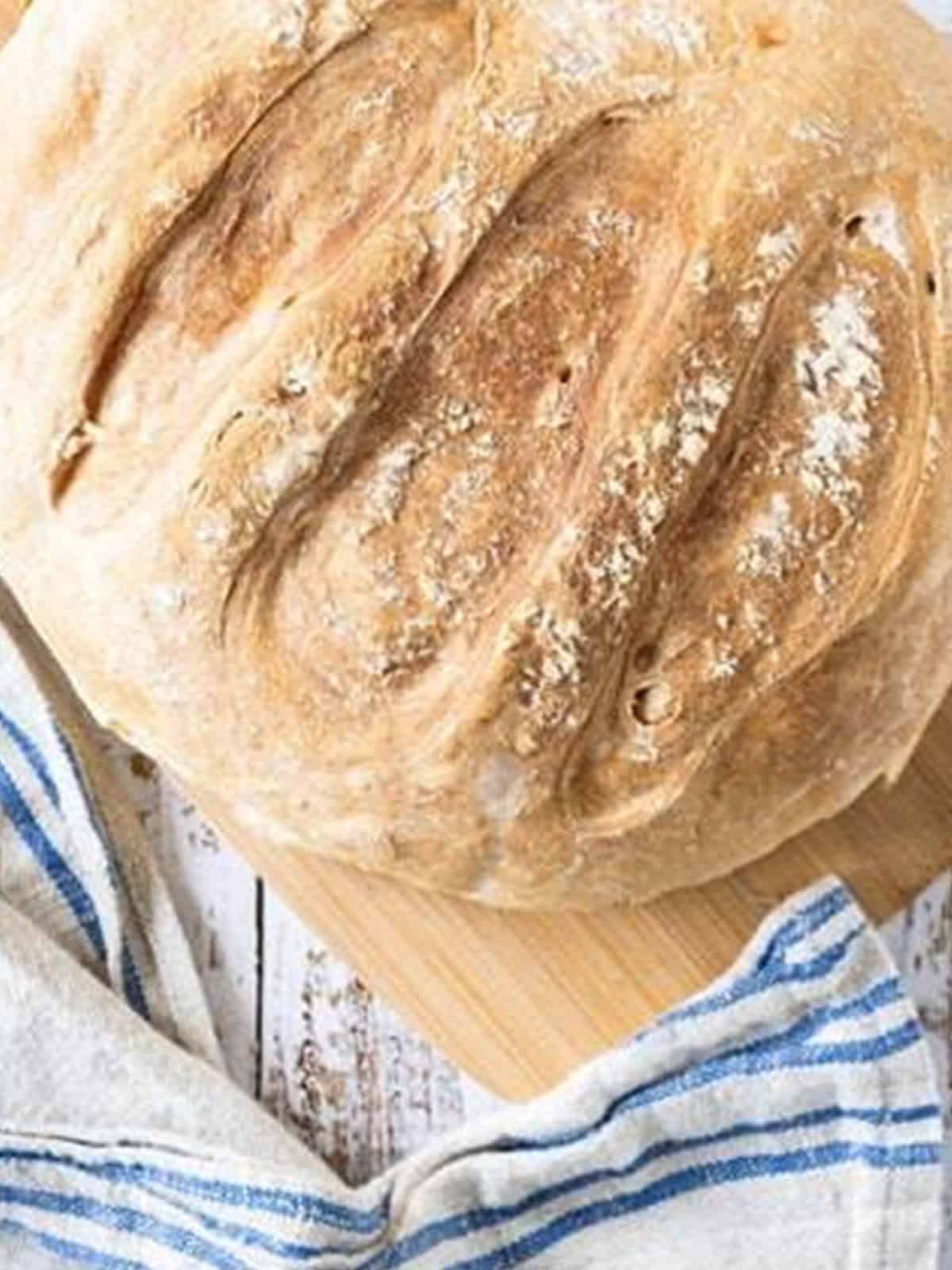 A finished golden brown sourdough bread loaf baked in a Dutch oven for sourdough bread recipe.