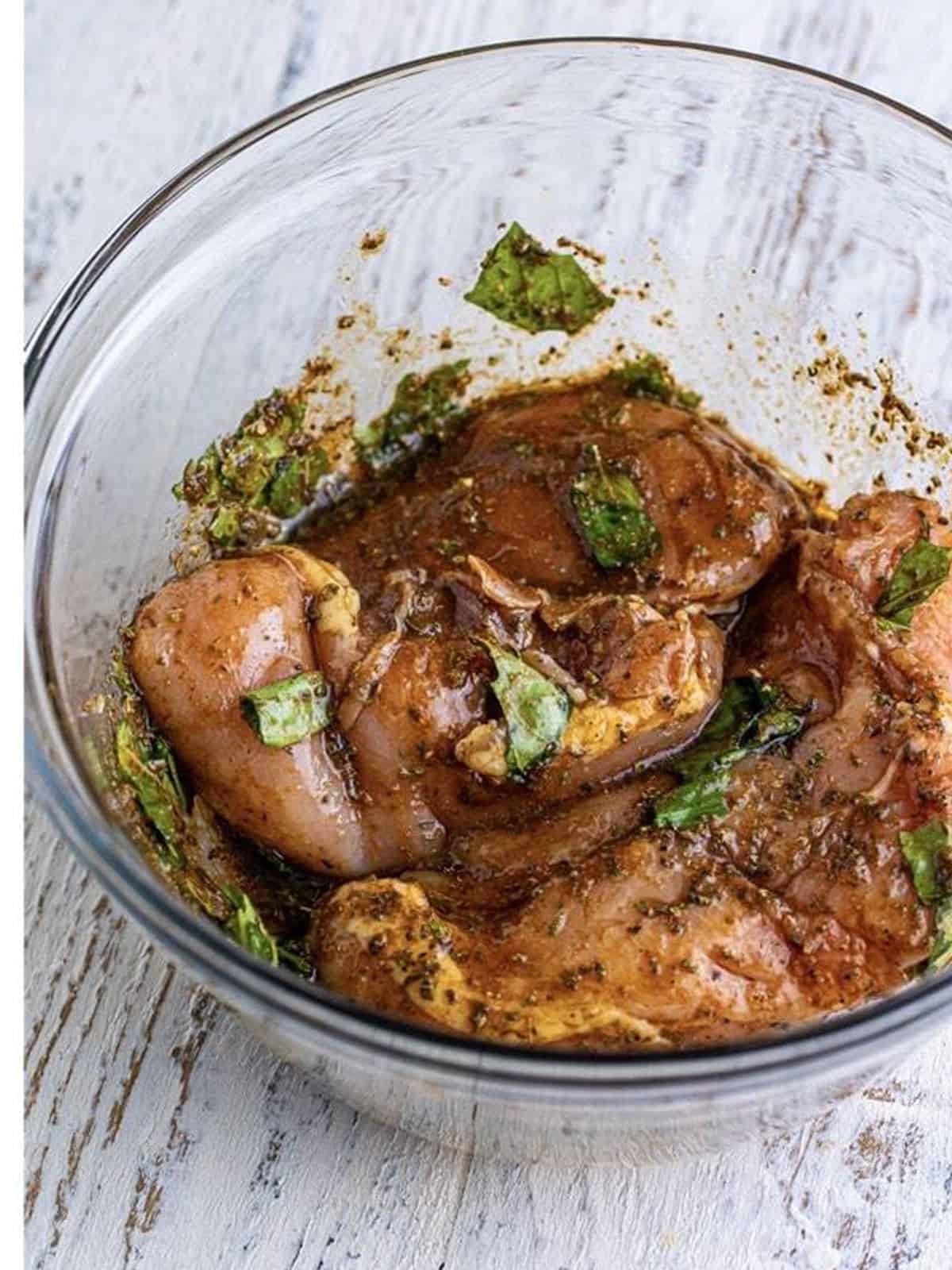 Chicken breasts coated in balsamic herb marinade in a glass bowl before sous vide cooking.