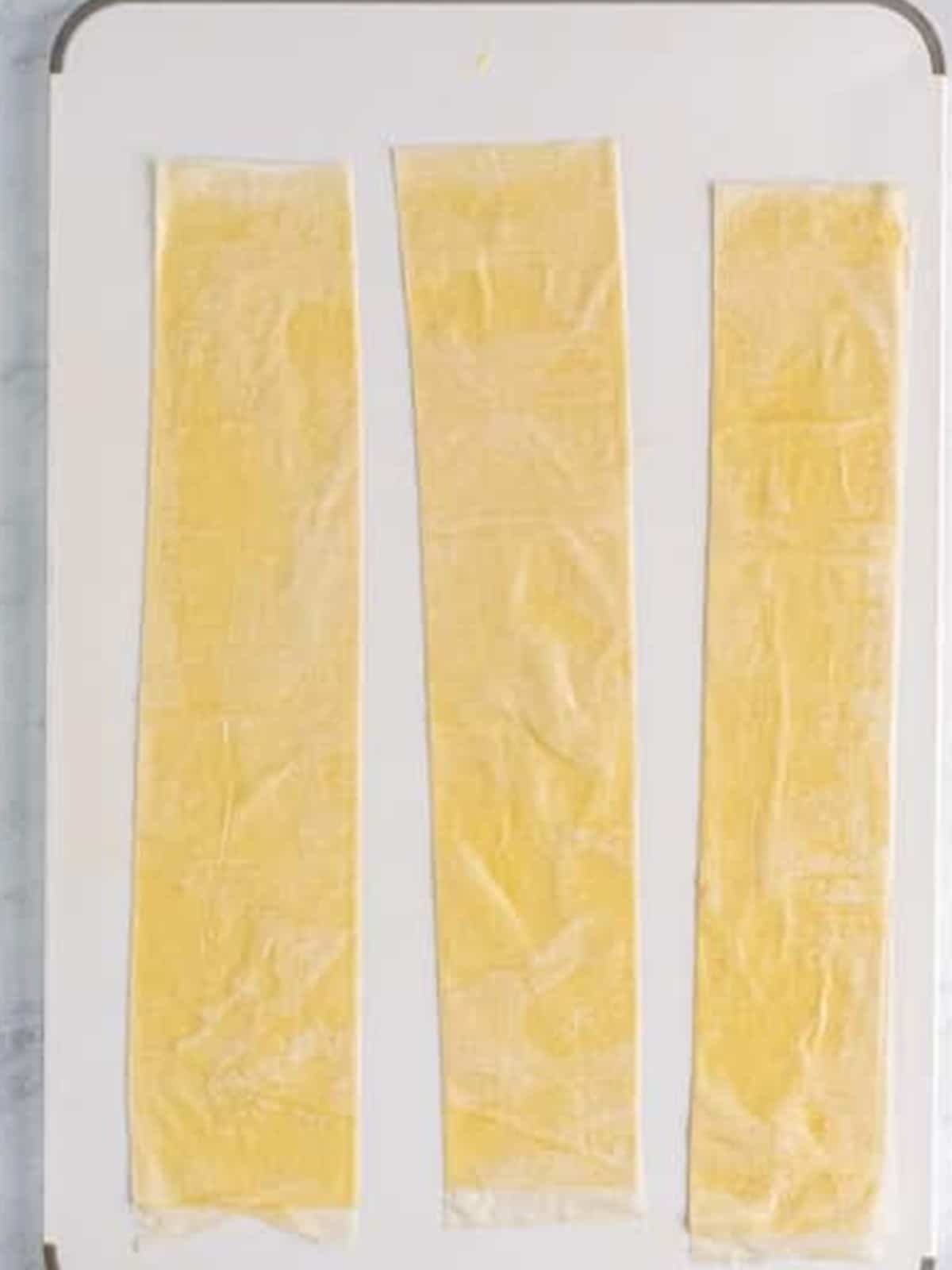 Phyllo dough cut into long strips and brushed with butter for spanakopita triangles.